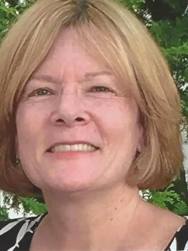 Smiling woman with short blonde hair outdoors.