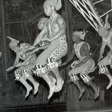 Group of men in traditional attire jumping in a synchronized dance.