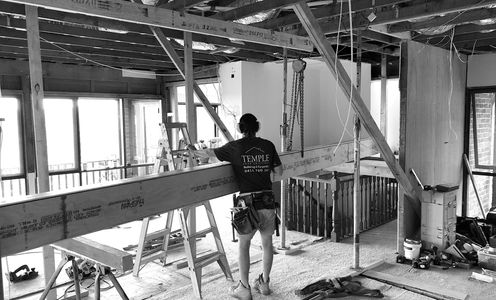 Worker in a construction site measuring a large beam indoors.