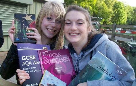 Two happy girls holding school GCSE books about English. 