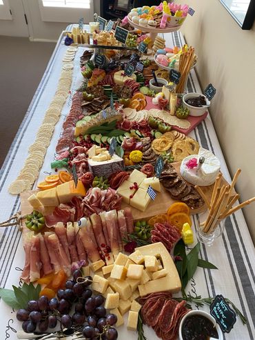 A lavish charcuterie spread with meats, cheeses, fruits, and sweets on a long table.