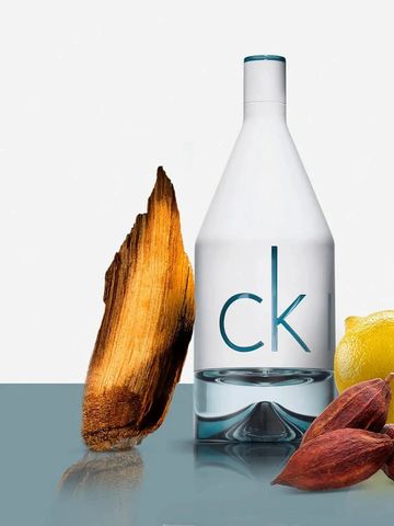 Botella de perfume ck con madera y frutas al lado.