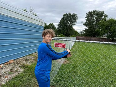 Fourth generation fence helper, finishing up a 4 foot chain-link residential fence installation