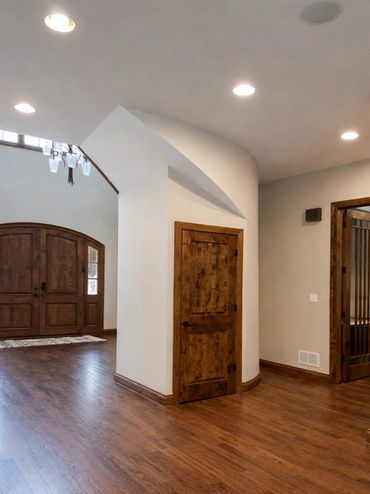 Wooden doors and hardwood floors in a spacious, well-lit hallway.