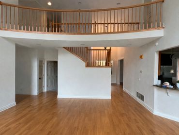 Spacious empty room with wooden floor and balcony railing.