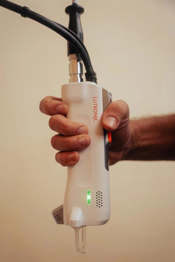 Hand holding a white Lutronic medical device.