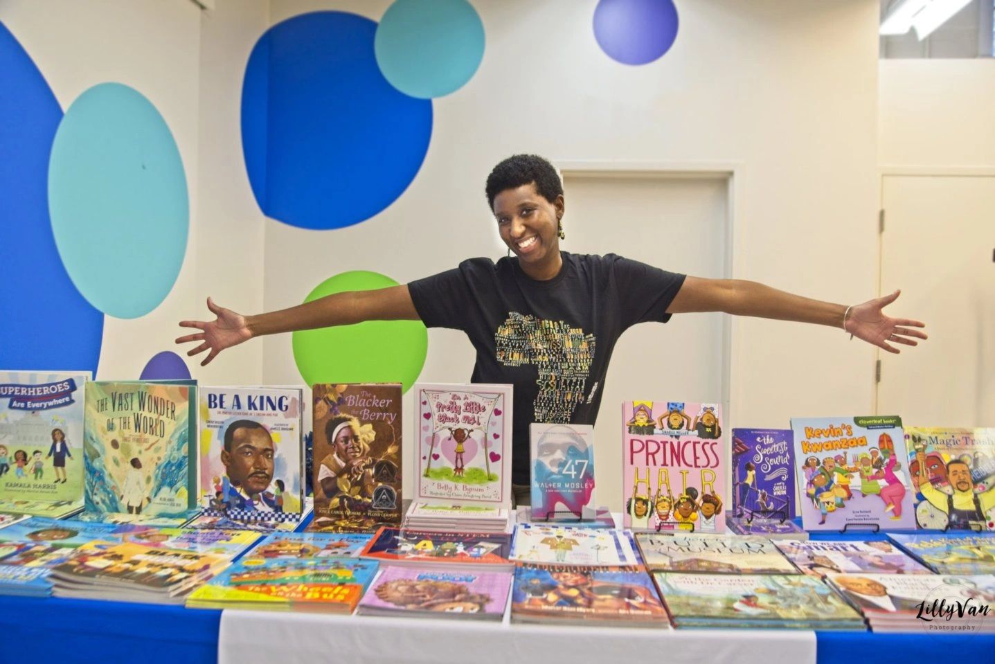Happy person showcasing a table full of colorful children's books.