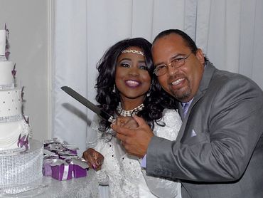 A happy couple cutting a decorated wedding cake together at their reception.