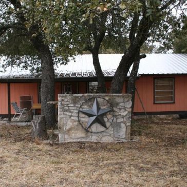 Ranch house with metal star hanging on back of BBQ pit.