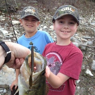 2 boys wearing GBL hats with fish they caught