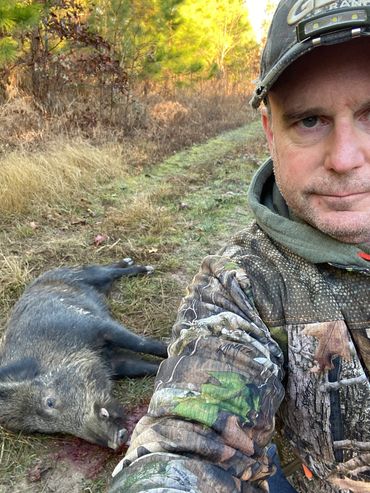 Hunter with GBL hat and harvested pig