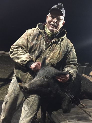 Hunter posing with hog in back of truck.