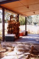 View of porch with wood stack and coolers.