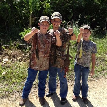 3 boys wearing GBL hats showing off iguana harvest