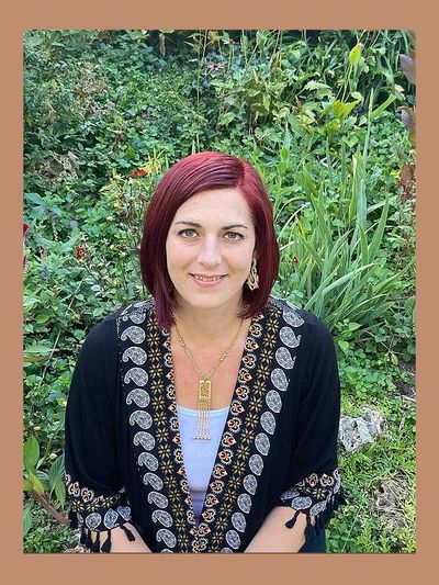 Woman with red hair in black patterned shawl outdoors.