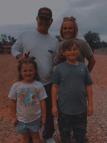 A happy family of four posing outdoors on a rocky path.