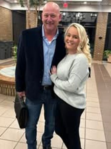 A man and woman posing happily indoors near a fountain.