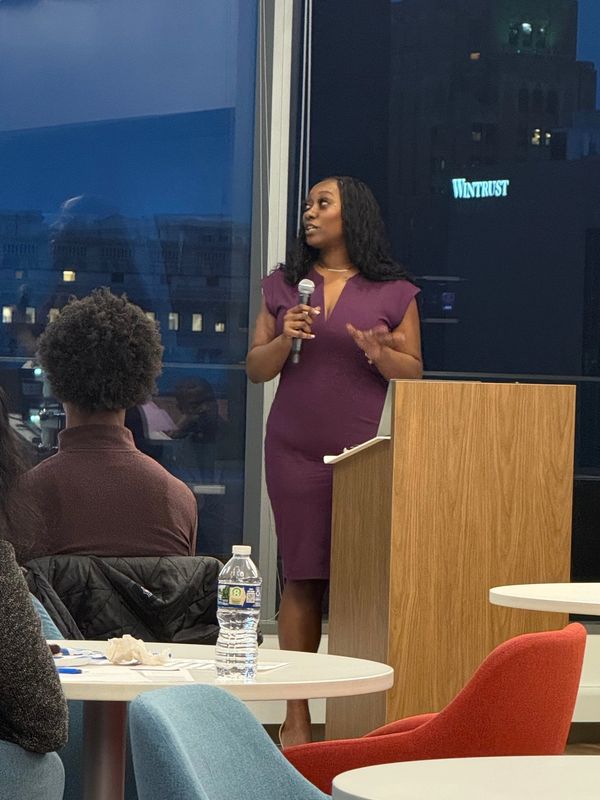 Woman in purple dress speaking with a microphone in a modern meeting room.