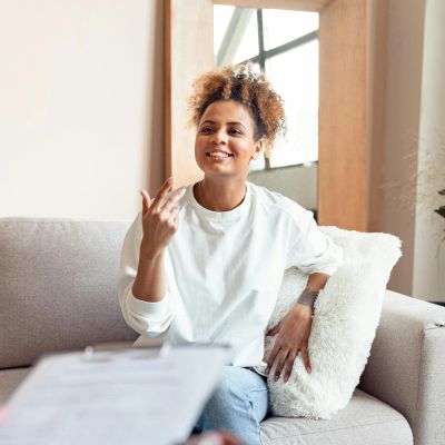 A woman happily sharing her thoughts during a conversation on a couch.