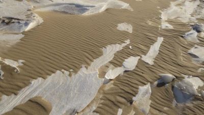 Sand dunes with patches of melting snow or ice.