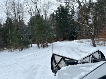 Snowplow clearing a snow-covered forest road.