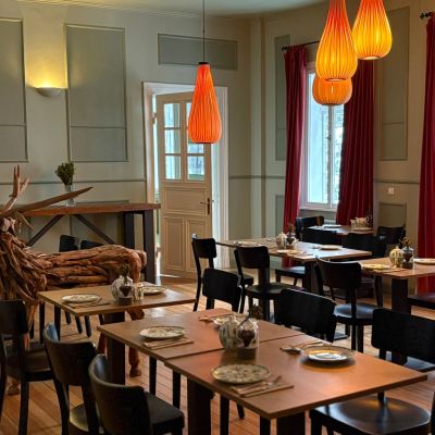 Cozy dining area with wooden tables, black chairs, and warm orange pendant lights.