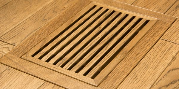 Wooden floor vent blending seamlessly with hardwood flooring.