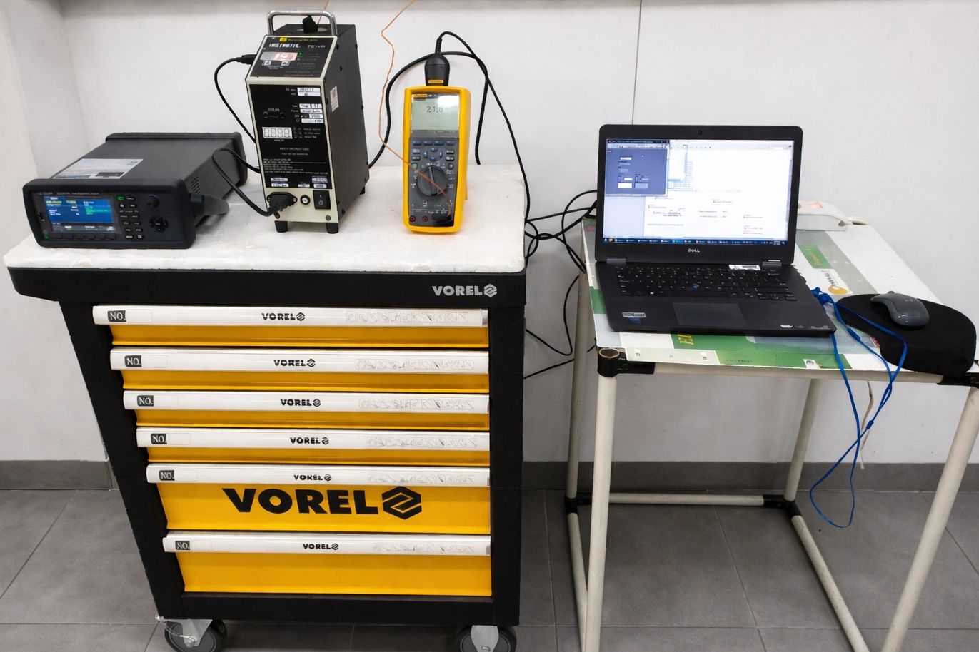 Electronics testing setup with measurement devices and laptop on workbenches.