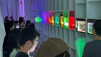 People observing illuminated displays in a dimly lit gallery.