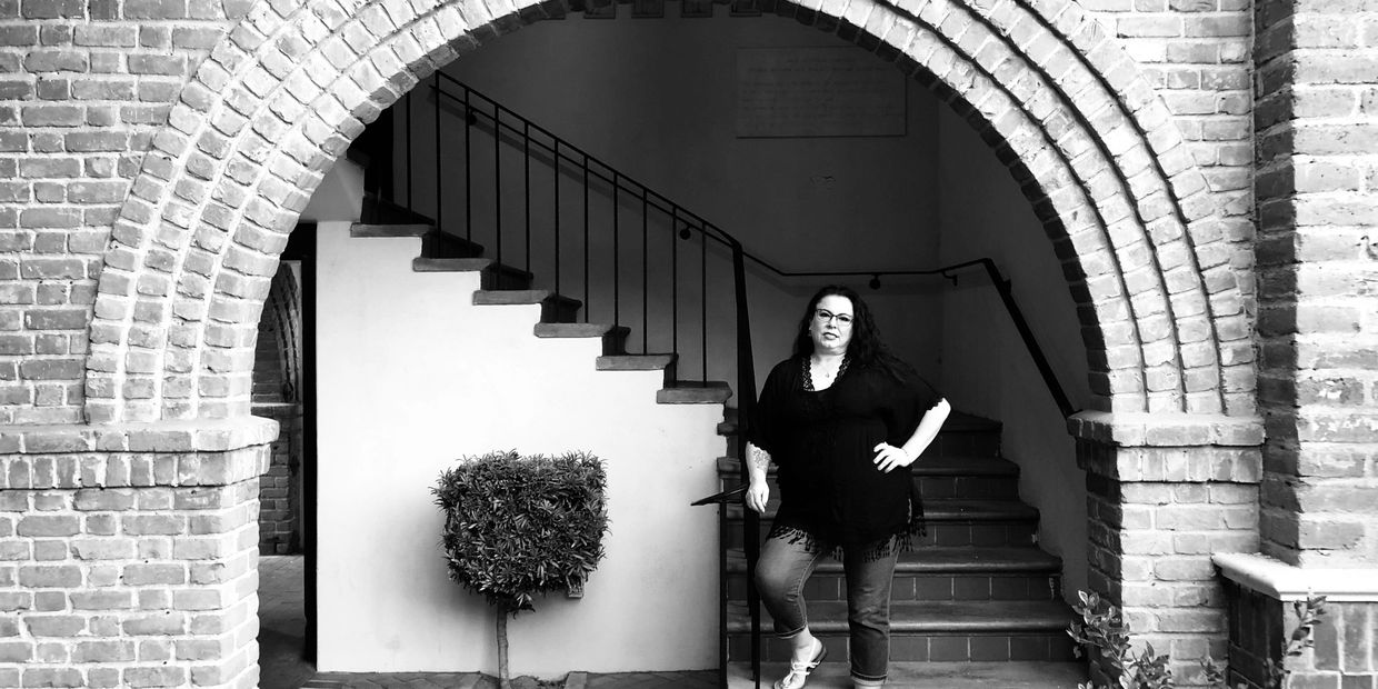 photo of jennica klemann standing in front of a staircase under a brick arch;
