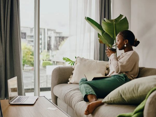 Woman relaxing on sofa with cup and laptop.