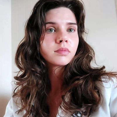 Young woman with long wavy hair looking thoughtfully ahead.