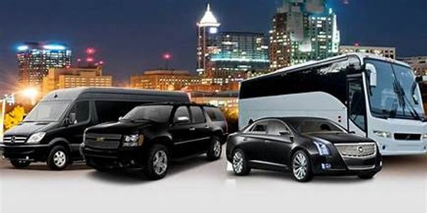 A fleet of black luxury vehicles and a bus with a city skyline at night.