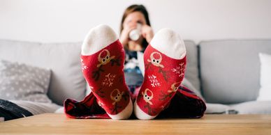 Woman sitting on sofa with her feet up, drinking a mug of hot drink