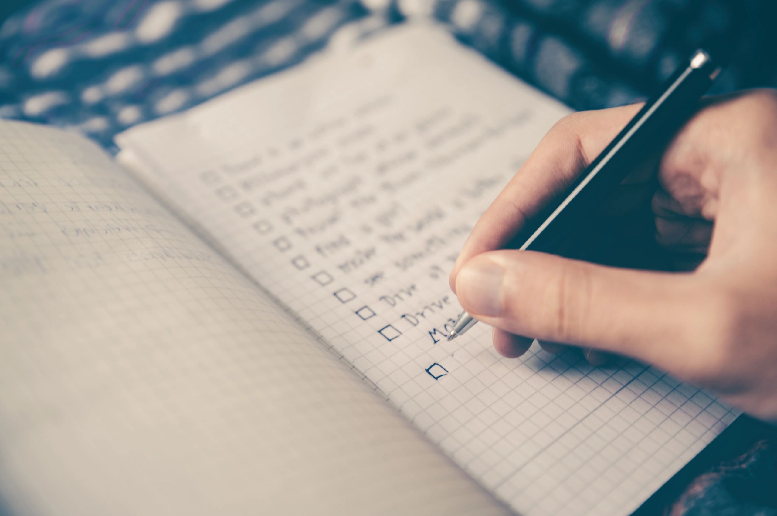 Hand writing a checklist in a notebook with a pen.