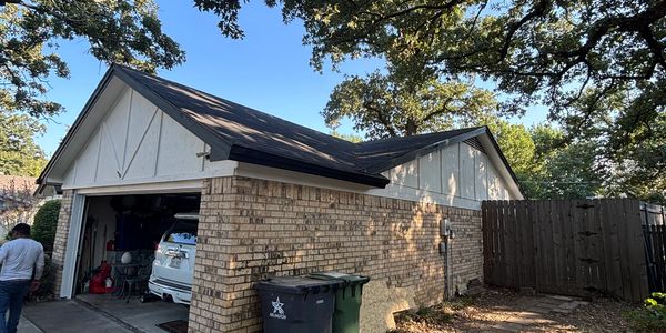 Brick house garage with a car and trash bins.
