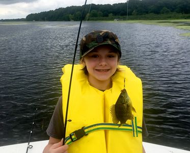 A kid wearing a yellow life jacket and holding a fishing rod