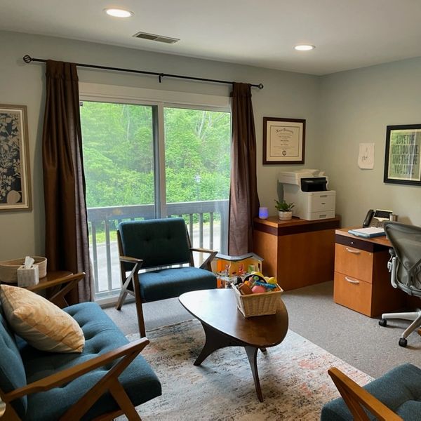 Cozy home office with wooden furniture and large window overlooking greenery.