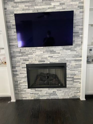 TV mounted in stone above the fireplace.