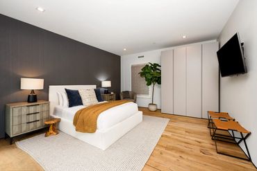 Modern bedroom with neutral tones, wooden flooring, and cozy accents.