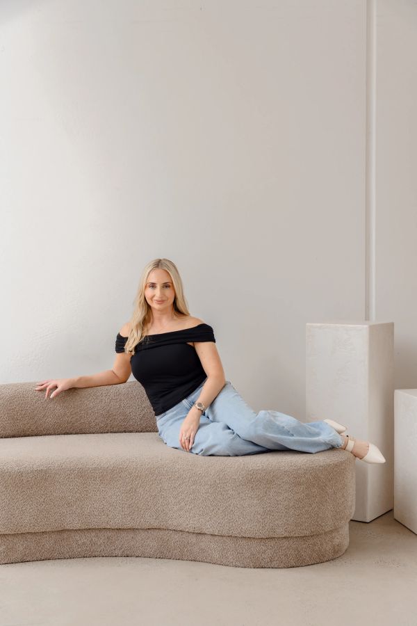 Blonde cosmetic nurse woman relaxing on a textured beige sofa.