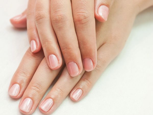 Well-manicured hands with light pink nail polish.