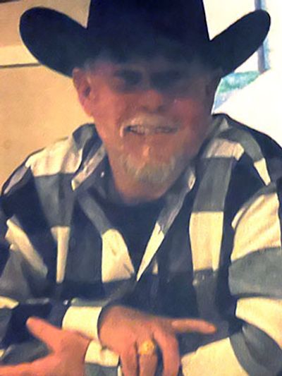 Man in a checkered shirt and cowboy hat smiling.