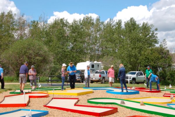 People enjoying a sunny day playing mini golf outdoors.