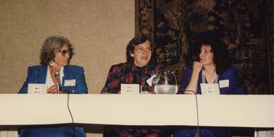 Three women sit at a table while presenting their scholarship.