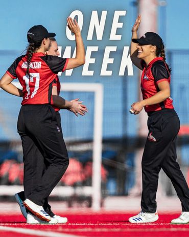 Female cricketers celebrating with high-fives on the field, wearing Gibraltar team jerseys.