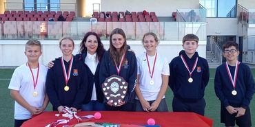 Young athletes with medals and trophy on a sports field podium.