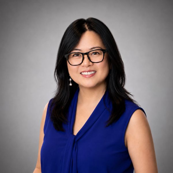 Woman with glasses in a blue sleeveless top smiling.