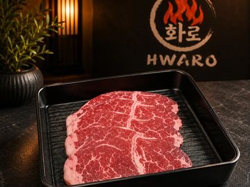 Raw marbled beef slices in a black tray, ready for grilling.