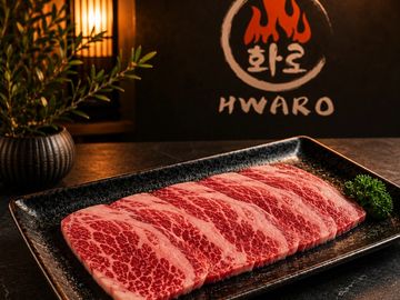 Marbled beef slices arranged on a black plate with HWARO logo in the background.